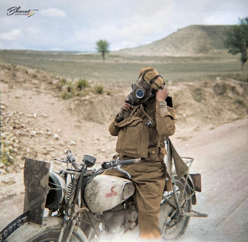 1942 年 3 月 3 日、キプロスでの 50 マイルのオートバイ試運転中にガスマスクを着用し、ノートン モデル 16H に乗ったインド人派遣ライダーのカラー化された写真。[1244x1217]