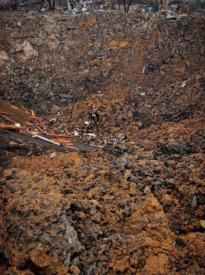 ロシアのFAB-500滑空爆弾によって引き起こされた爆弾クレーターの中に立つウクライナ兵士