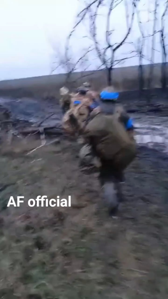 重い荷物を積んだウクライナ兵が泥の中を陣地まで行進する。