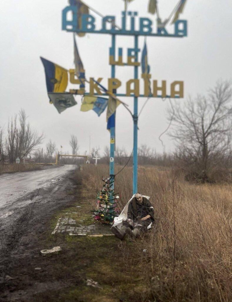 アヴディウカ肉挽き機の入り口のクリスマスツリーの横に立てかけられたロシア人の死体