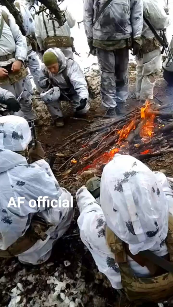 雪上迷彩服を着たウクライナ軍兵士がたき火で暖をとっている。