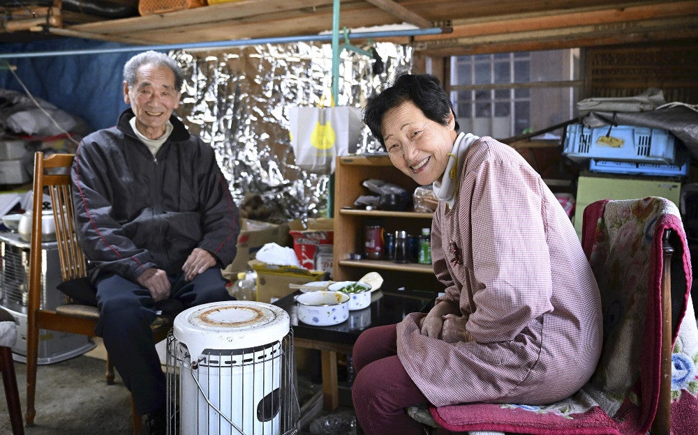 ３月から正院小学校の仮設住宅に入居した市保羊作さん（左）と妻・百合子さん。「住み慣れたこの町に暮らし続けたい」。片付けで訪れていた自宅のガレージで笑顔を見せた（石川県珠洲市で）