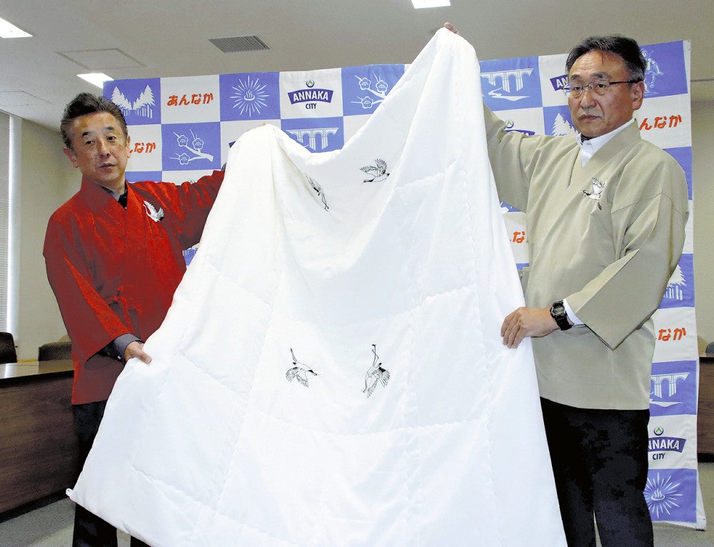 開発した作務衣を着て掛け布団を紹介する土屋常務（右）＝１６日、群馬県安中市で