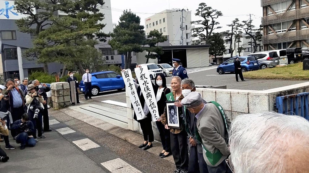 判決を受けて「国の責任を認めず」などと記した旗を掲げる原告側の弁護士ら（１８日、新潟市の新潟地裁前で）