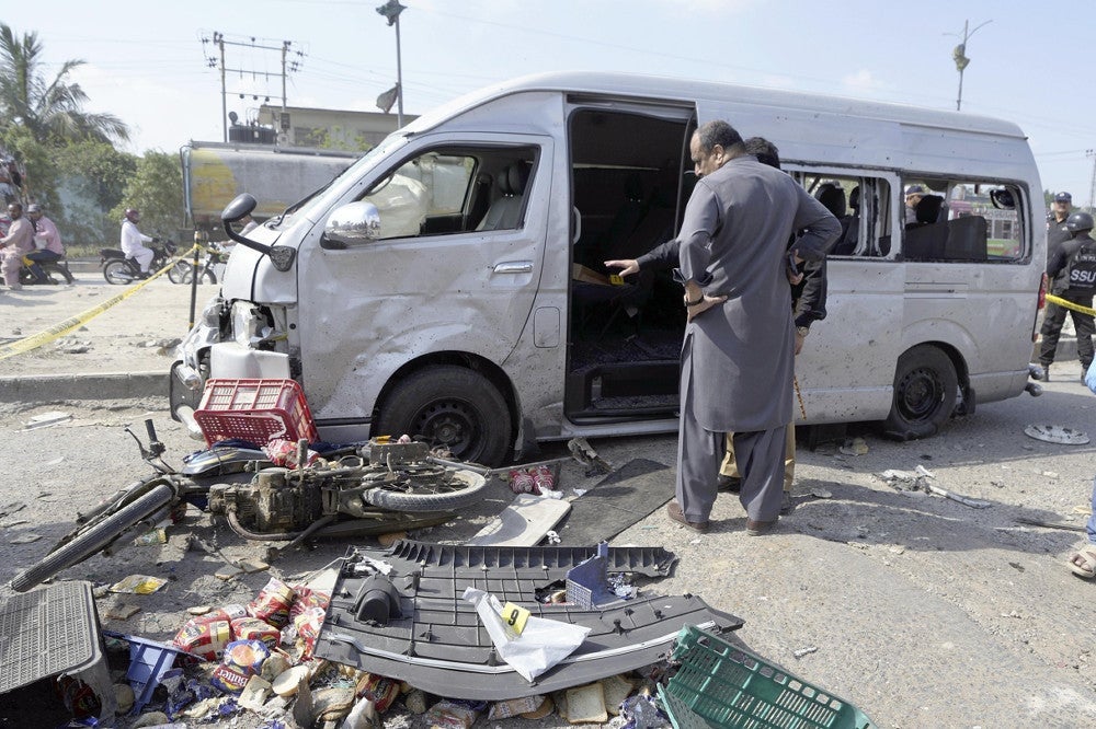 １９日、パキスタン南部カラチで、襲撃された車両を調べる捜査員＝ＡＰ