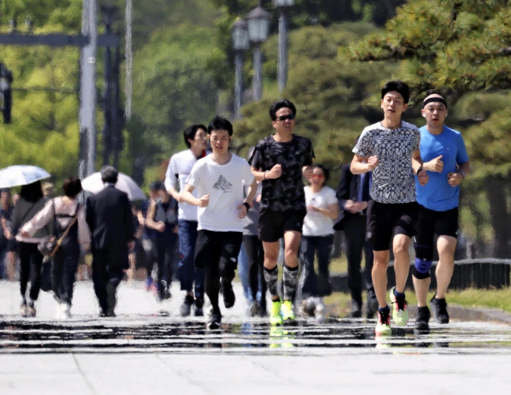 気温が上昇するなか、皇居周辺でランニングをする人たち（２０日午前、東京都千代田区で）＝永井秀典撮影