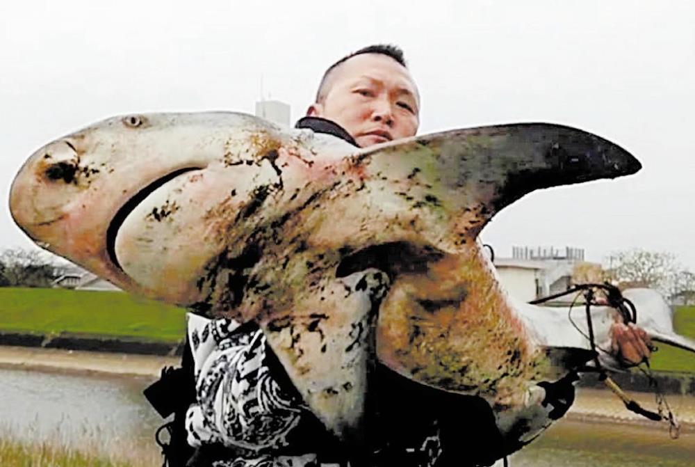 釣り上げたオオメジロザメを持ち上げる河野さん（１４日、宮崎市で）＝河野さん提供