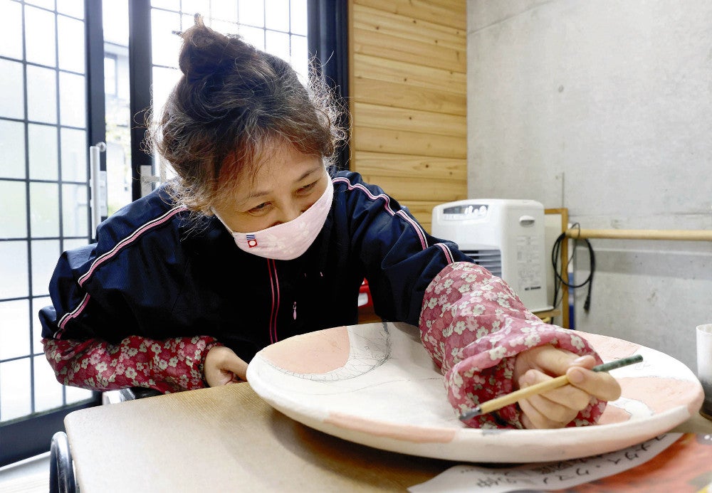 大皿に絵付けをする鈴木さん（２１日、兵庫県西宮市で）＝枡田直也撮影