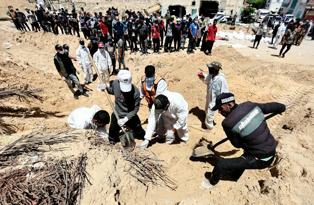 ナセル病院の敷地内に埋められた遺体に集まるガザ住民（２１日）＝写真はロイター