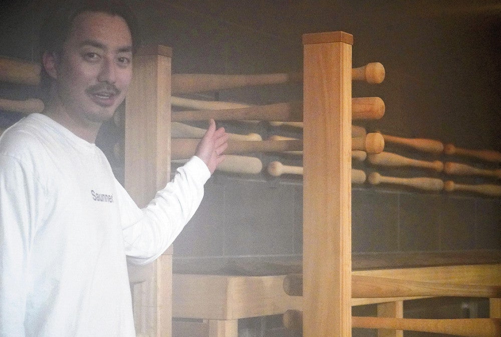 サウナスペースを紹介する小川さん。背もたれなどにバット形の木材を使っている