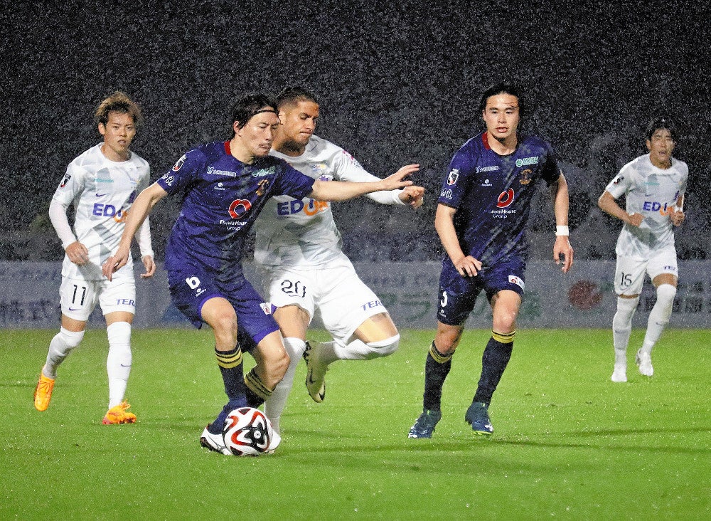 照明に照らされたピッチで相手選手と競り合う奈良クラブの選手（２４日夜、奈良市で）