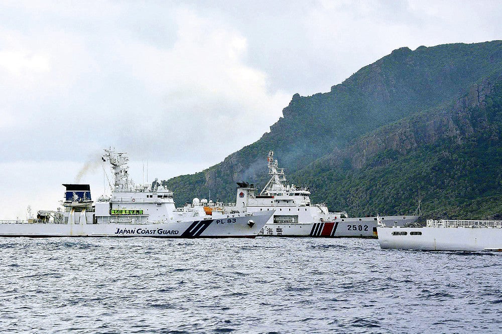 中国海警局の船（中央）が調査船に接近しないように警戒する海上保安庁の巡視船２隻。奥は魚釣島北部（２７日、尖閣諸島沖で）