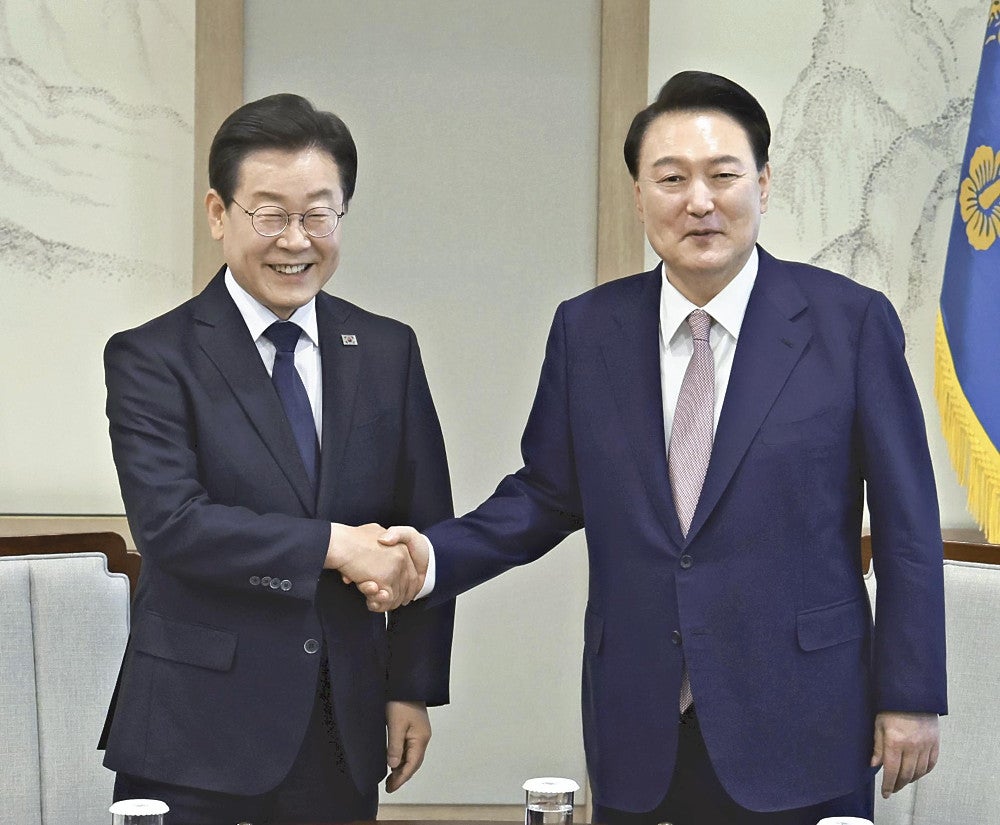 ２９日、ソウルで握手する尹錫悦大統領（右）と李在明氏＝聯合ＡＰ