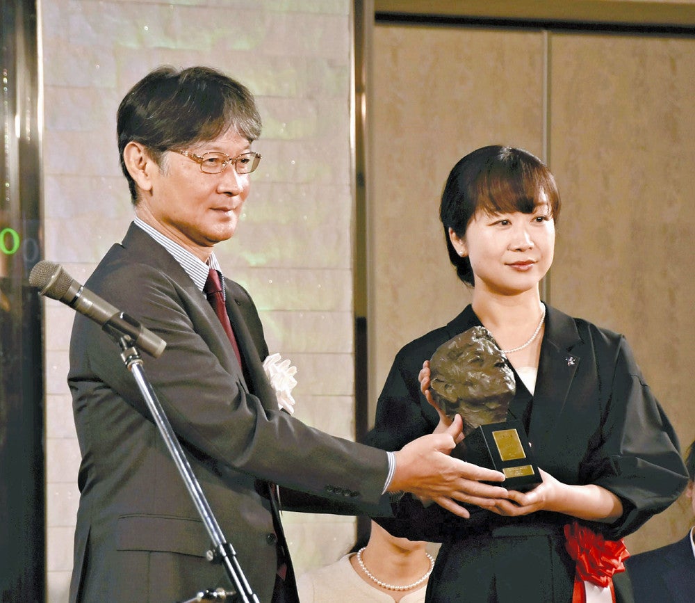 伊藤市長（左）からブロンズ像を受け取る佐藤さん