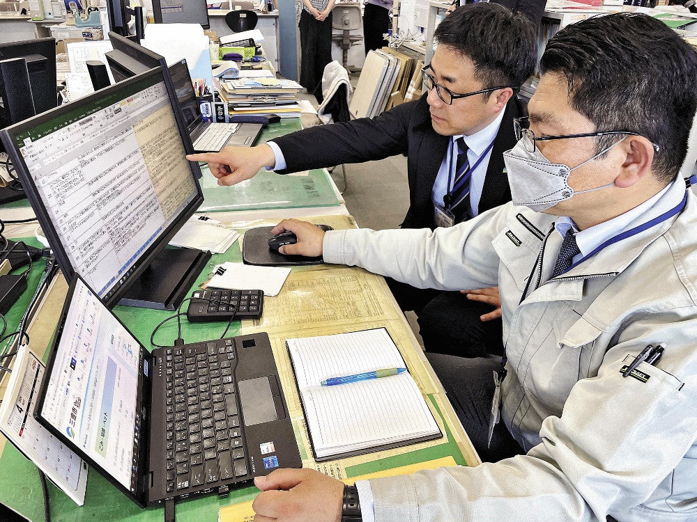生成ＡＩが表示した回答を読む香川県三豊市職員の岡崎さん（手前）と荒脇さん（香川県三豊市役所で）