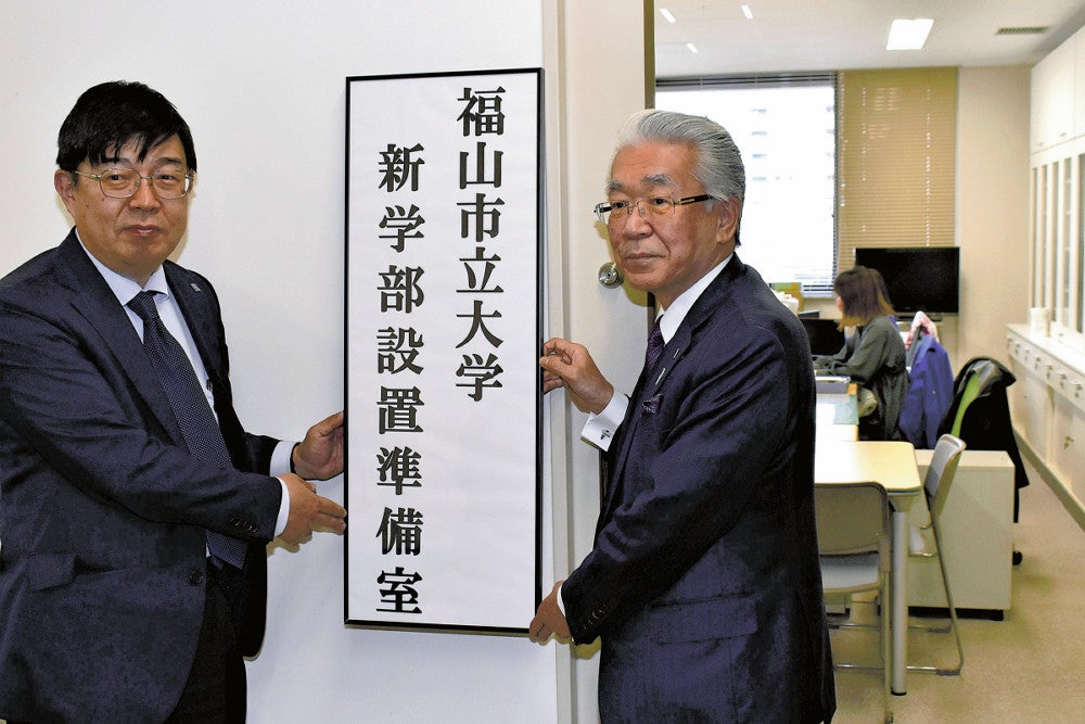 準備室の看板を掲げる佐藤理事長兼学長（右）（４月１２日、広島県福山市で）