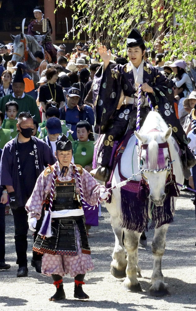 沿道の観光客らに手を振る源義経役の寺田さん（３日、平泉町の毛越寺で）＝松本茉莉撮影