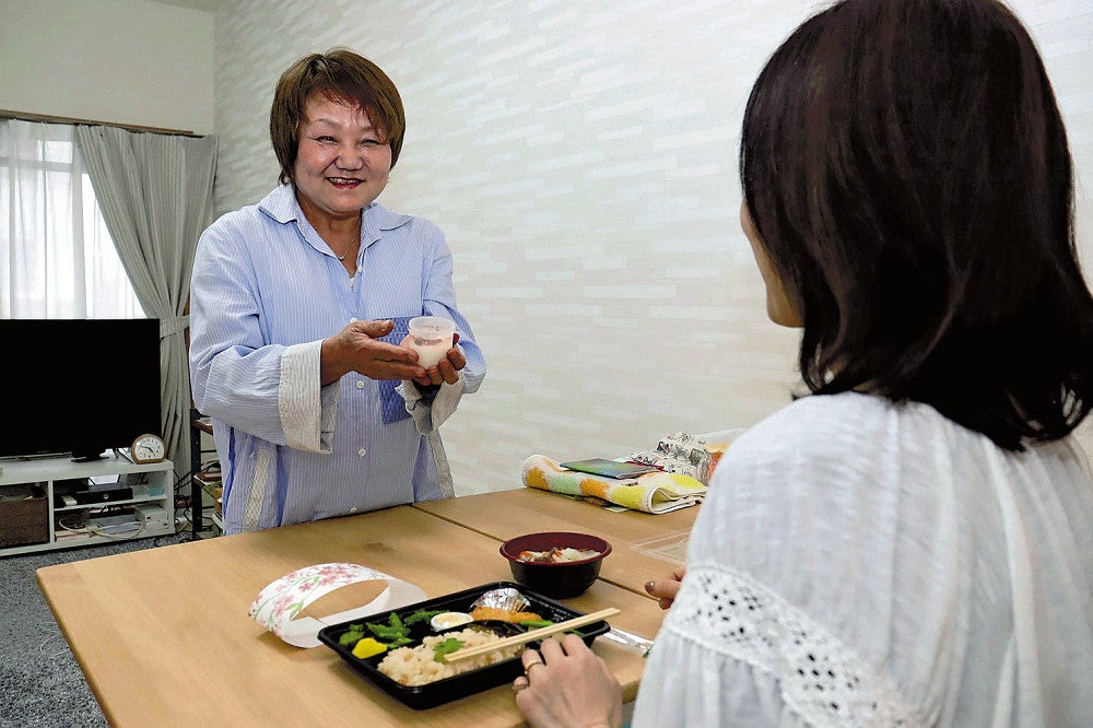 ファミリーハウスの利用者に手作り弁当を届ける高原さん（左）