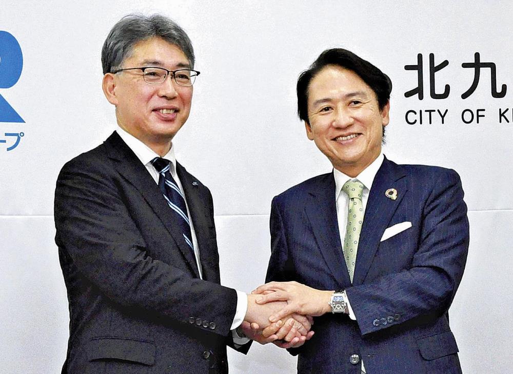 協定に調印して握手を交わすＪＲ西日本の魚本支社長（左）と北九州市の武内市長（７日午前１０時４９分、北九州市役所で）＝牟田口洸介撮影