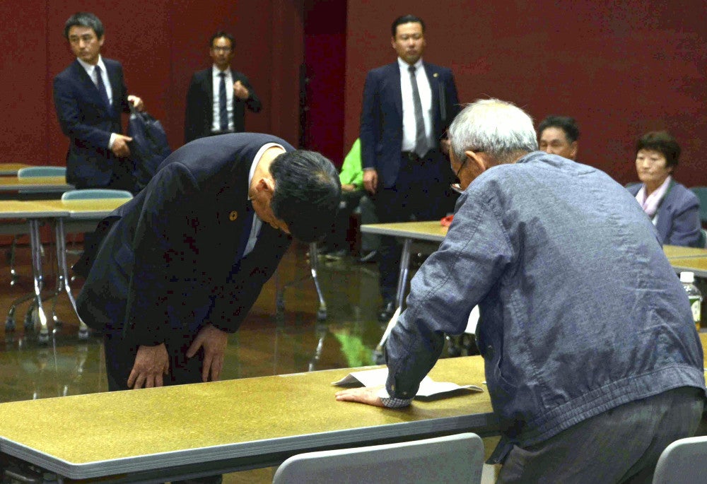 「水俣病被害市民の会」の山下善寛代表（右）に頭を下げる伊藤環境相（８日午後、熊本県水俣市で）＝白石一弘撮影