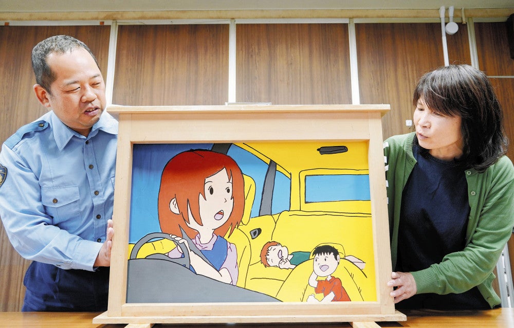 晃希ちゃんが亡くなった事故を描いた紙芝居を手にする交通安全指導員の茶野さん（右）と黒川巡査部長（滋賀県東近江市で）