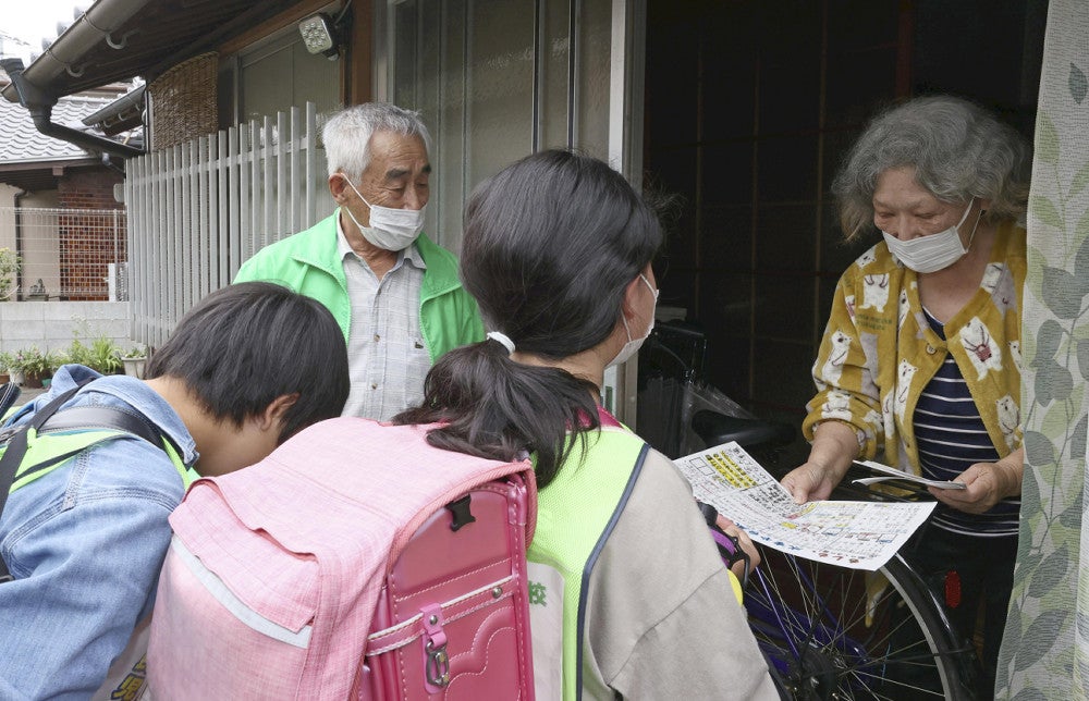 民生委員（左から２人目）と高齢者宅を訪れ、防災リーフレットを手渡すジュニア民生委員・児童委員たち（４月１７日、福岡県大牟田市で）＝佐伯文人撮影