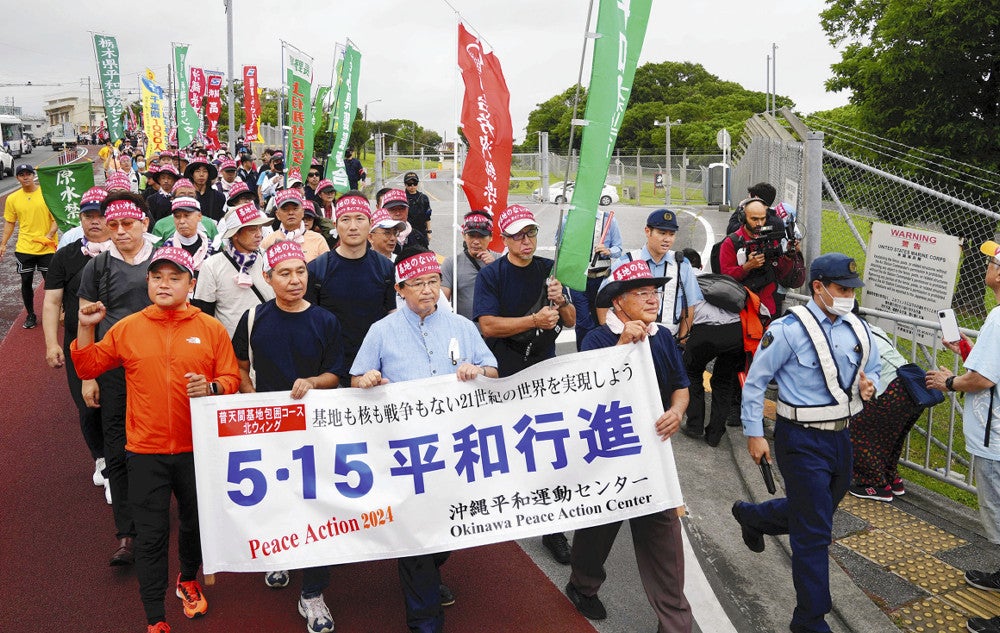 米軍普天間飛行場のゲート前を行進する参加者ら（１８日午前、沖縄県宜野湾市で）＝中島一尊撮影