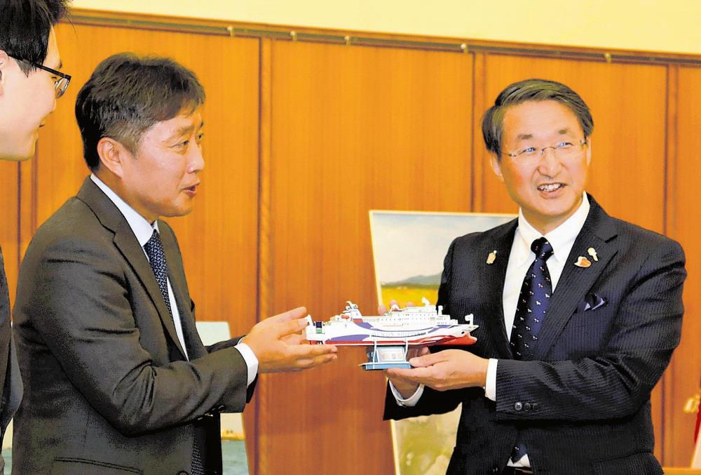 平井知事（右）と会談してイースタンドリーム号の模型を手渡す李社長（知事公邸で）
