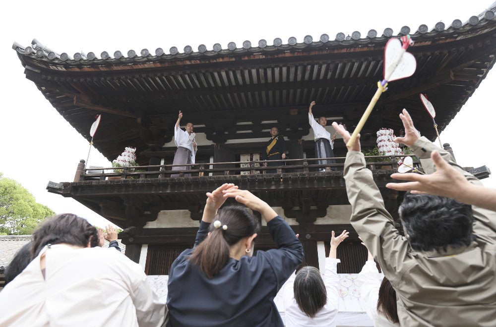 鼓楼からまかれる宝扇を受け取る参拝者（１９日午後、奈良市の唐招提寺で）＝宇那木健一撮影
