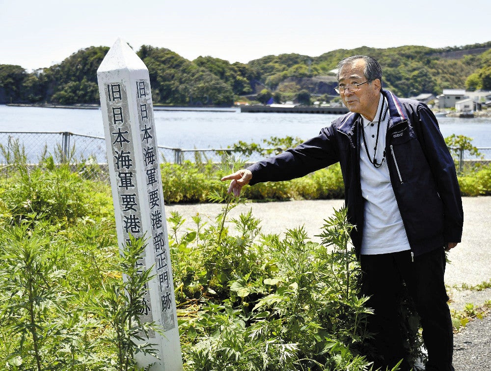 「旧日本海軍要港部正門跡」の標柱を示す俵さん（対馬市美津島町で）