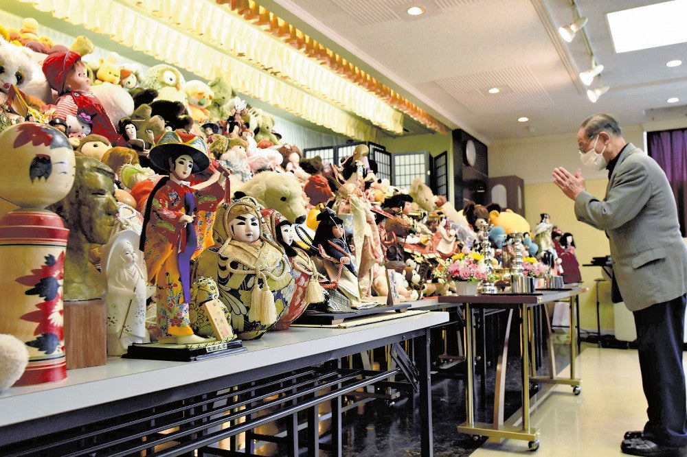 供養される人形の前で手を合わせる参列者（１９日、青森市で）