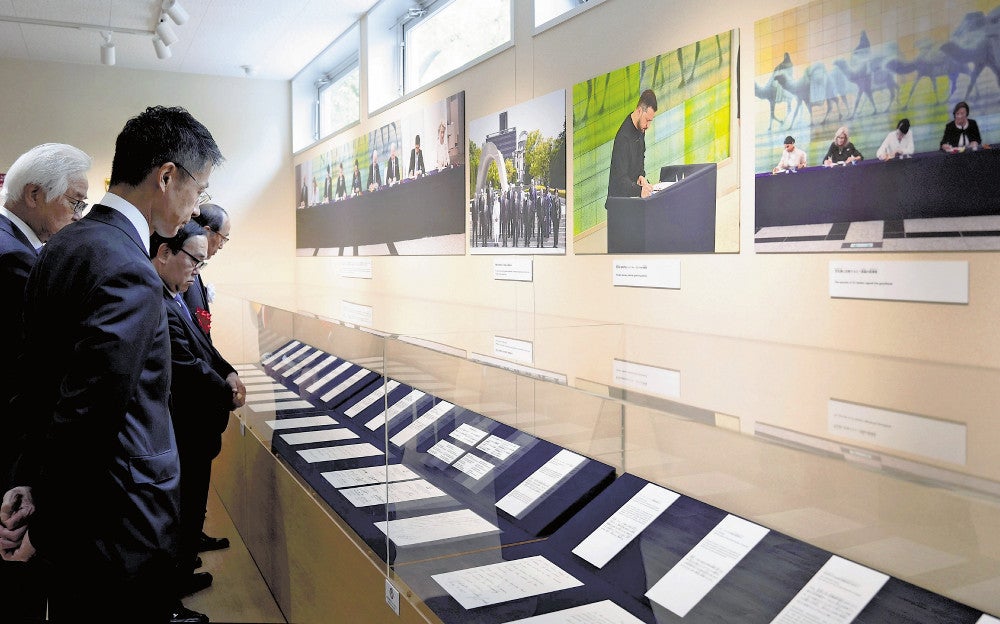 芳名録のレプリカに目を凝らす湯崎知事（手前）ら（広島市中区で）