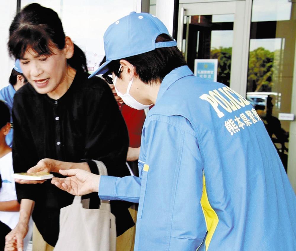 情報提供を求めるティッシュを受け取る買い物客