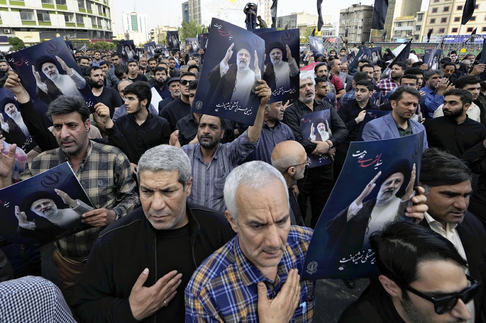 ２０日、イランの首都テヘラン中心部の広場でライシ師のポスターを掲げて追悼する人々＝ＡＰ