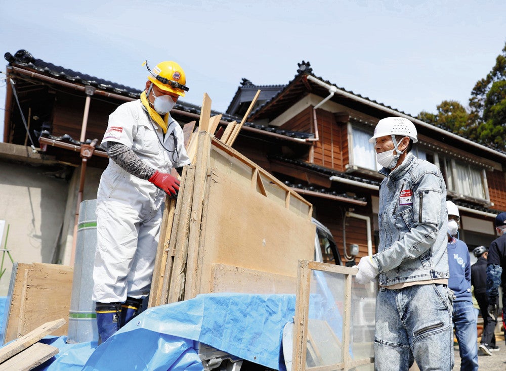 能登半島地震の被災地で、同僚と一緒に片付けのボランティアを行う安井義政さん（右）（４月７日、石川県志賀町で）＝横山就平撮影