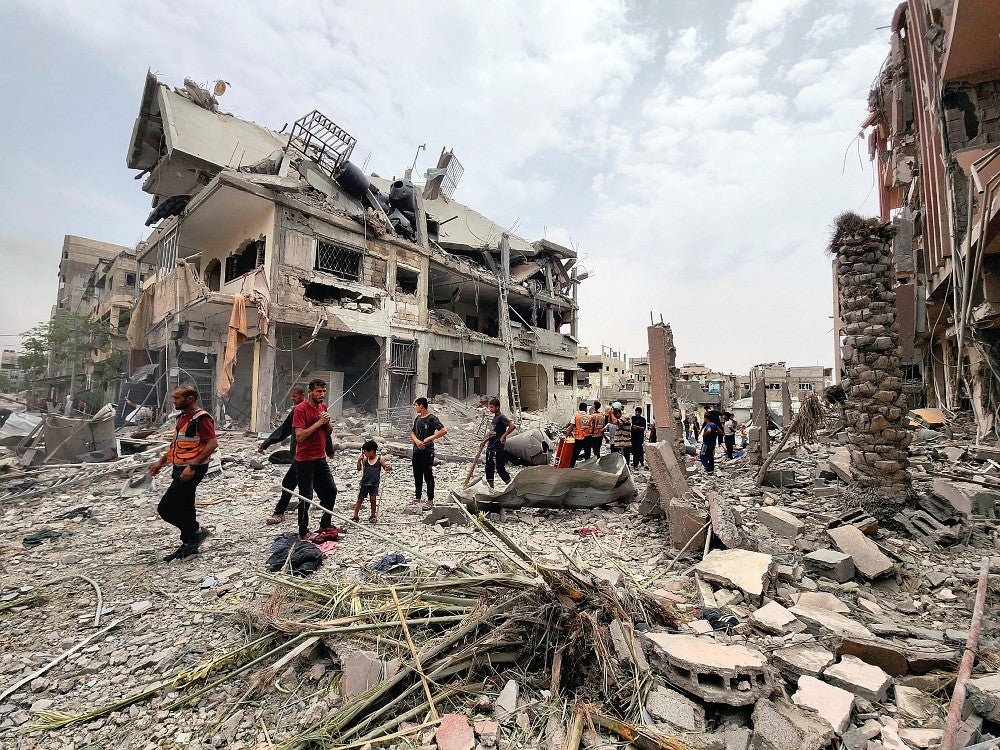 ２０日、ガザ北部ベイトラヒヤで、イスラエル軍に破壊された家屋を調べる人々＝ロイター