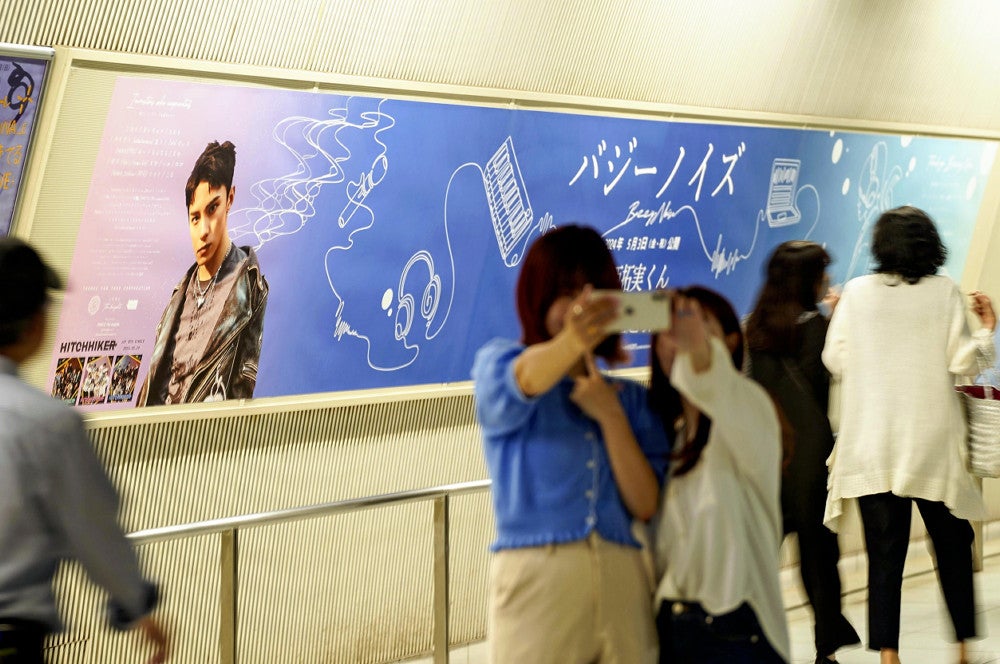 応援広告の前で写真を撮るファンたち（４日、横浜市西区のみなとみらい駅で）＝村松魁成撮影