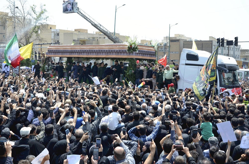 ２２日、テヘランで、ライシ大統領らのひつぎを乗せた車両を取り囲むようにして見送る市民＝吉形祐司撮影