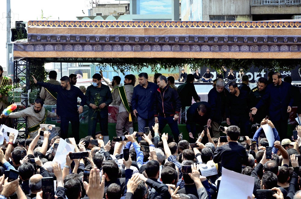 ２２日、テヘランで、ライシ大統領らのひつぎを乗せた車両を取り囲むようにして見送る市民＝吉形祐司撮影