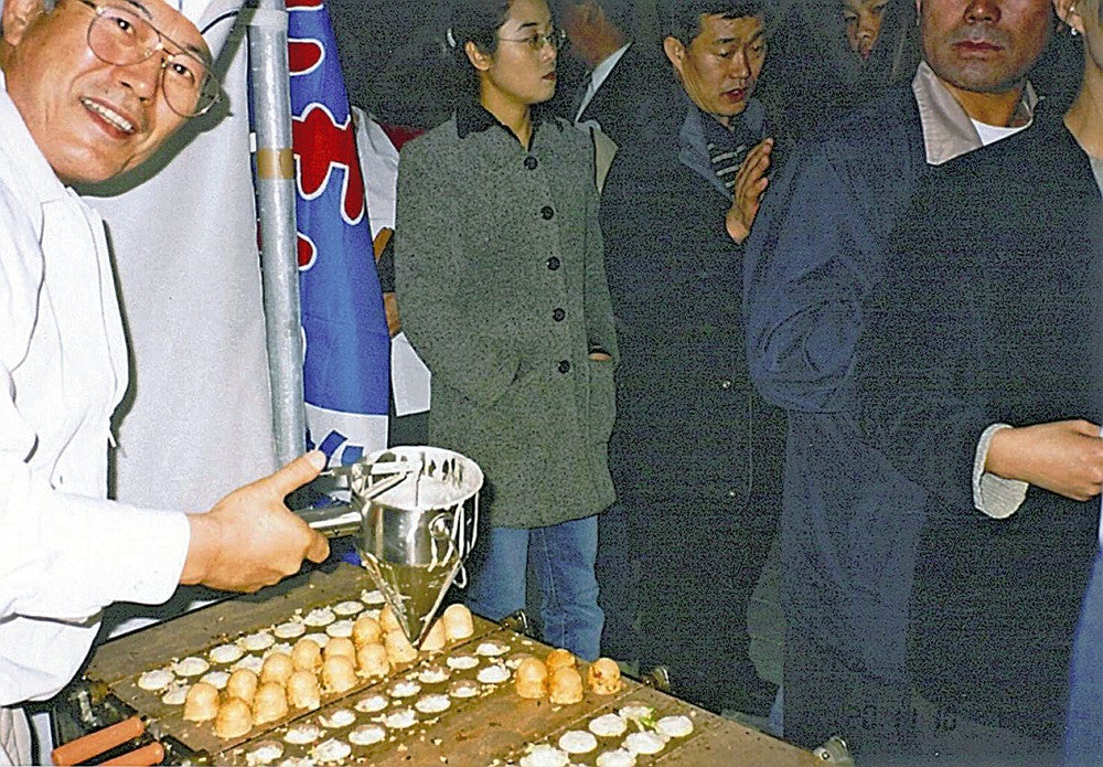 たこ焼きを焼く川邊さん（左）＝本人提供