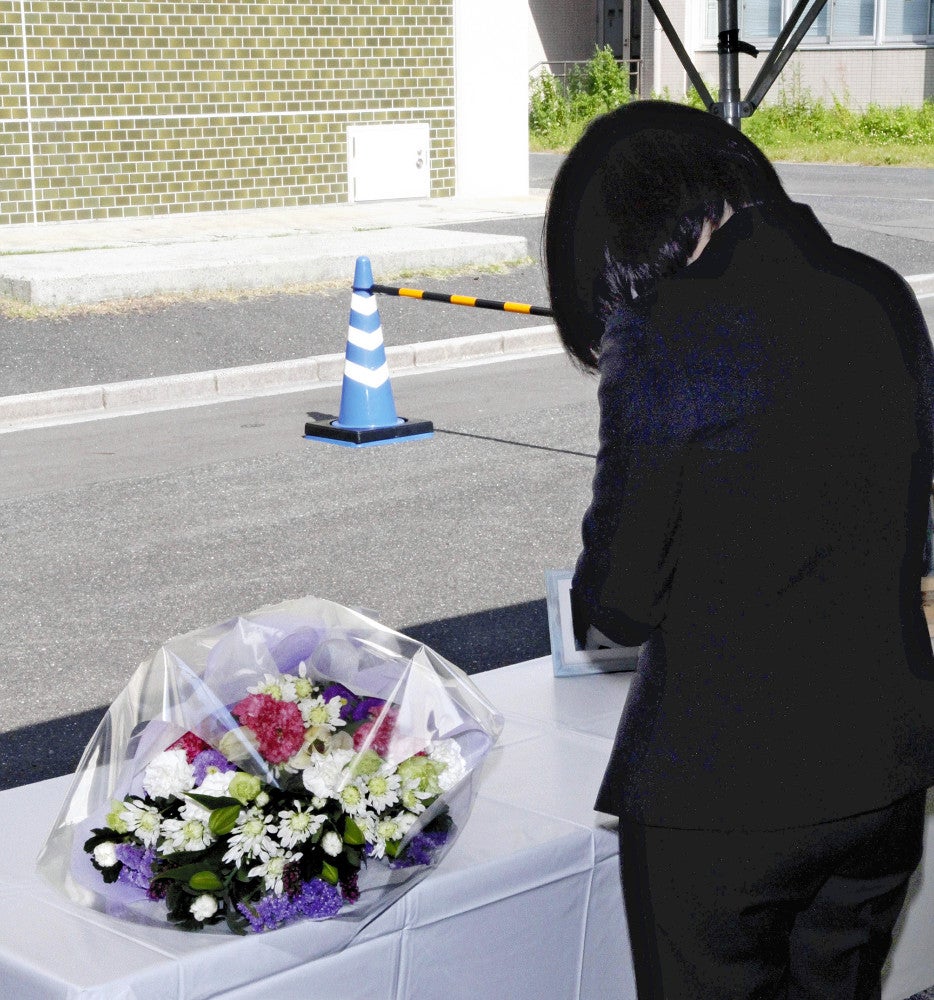 献花して祈りをささげる男子学生の母親