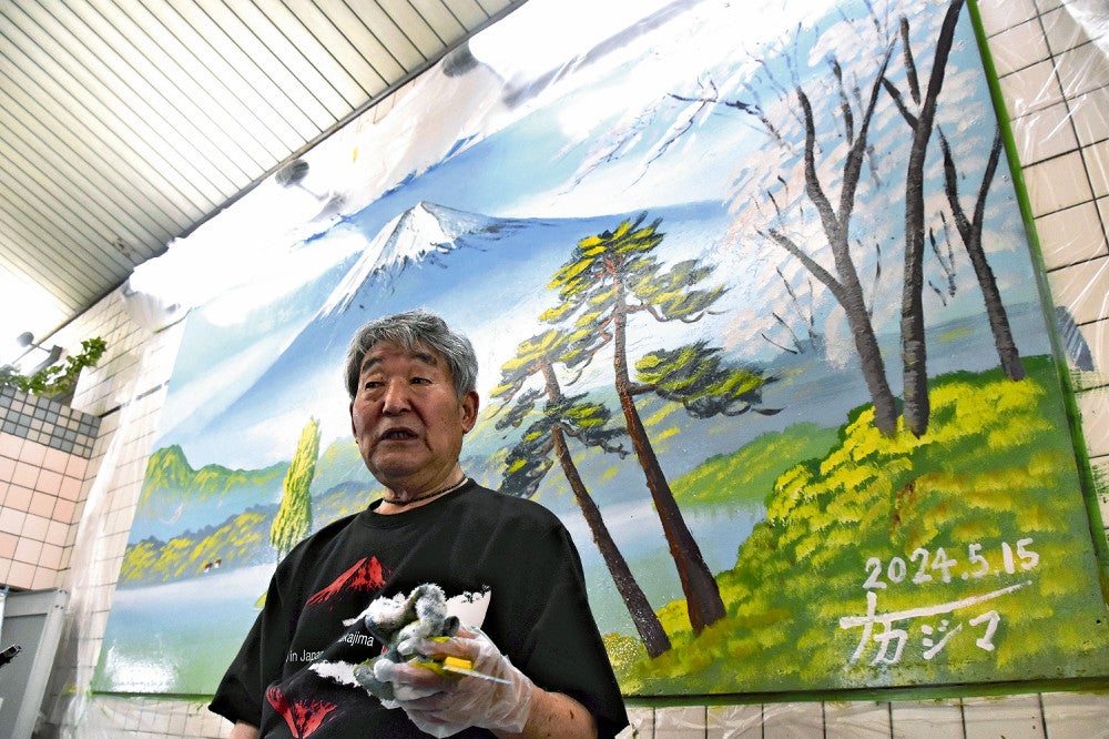 完成した女湯の銭湯背景画の前で観客からの質問に答える中島さん（大阪市東住吉区で）