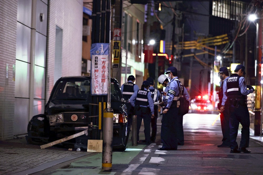 電柱に衝突したタクシーの周辺を調べる警察官ら（２５日午後９時４４分、福岡市中央区で）＝佐伯文人撮影