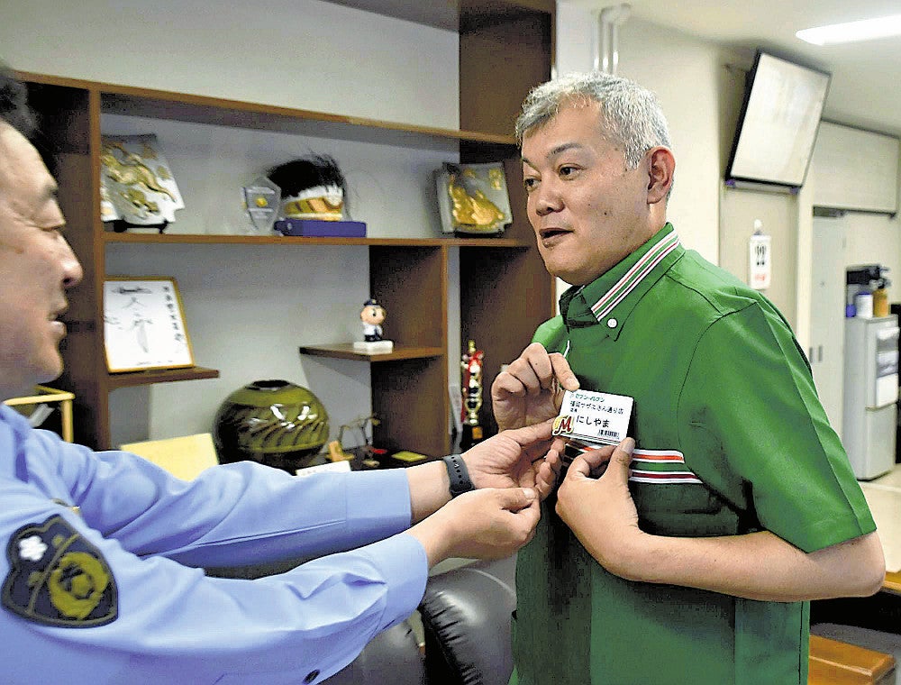 マイスターのバッジを桐原署長（左）から受け取り、身に付ける西山さん