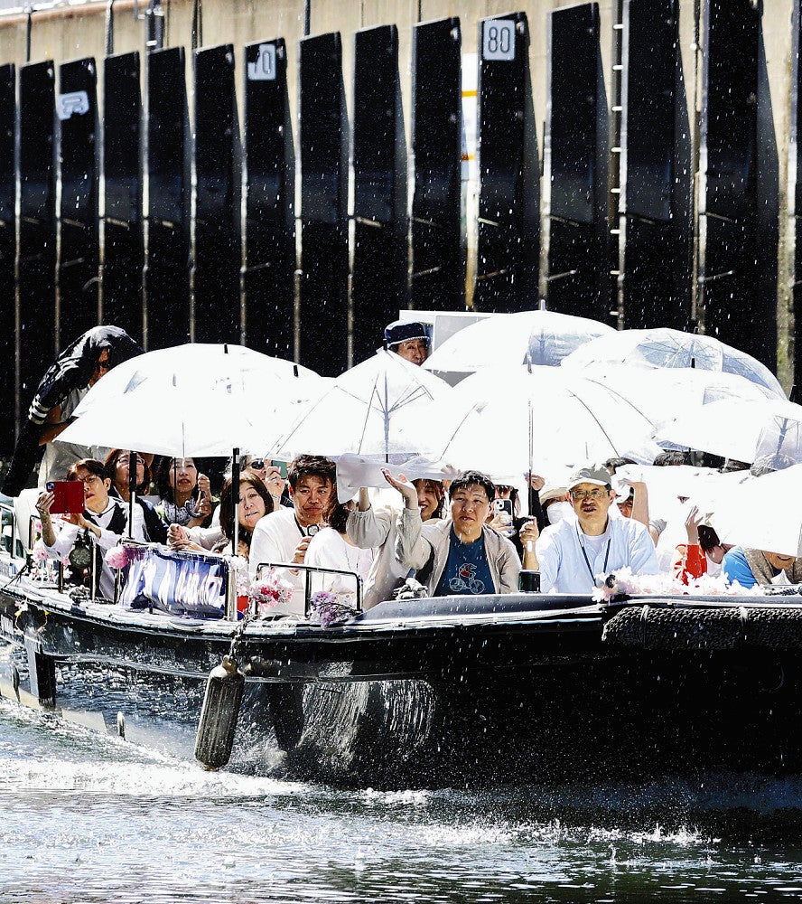傘を手に水滴がしたたる水門をくぐる観光客ら