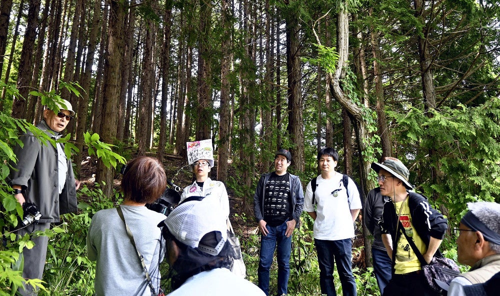 ヒバゴンの目撃情報があった場所で恵木さん（左）の話を聞くツアー参加者（広島県庄原市で）