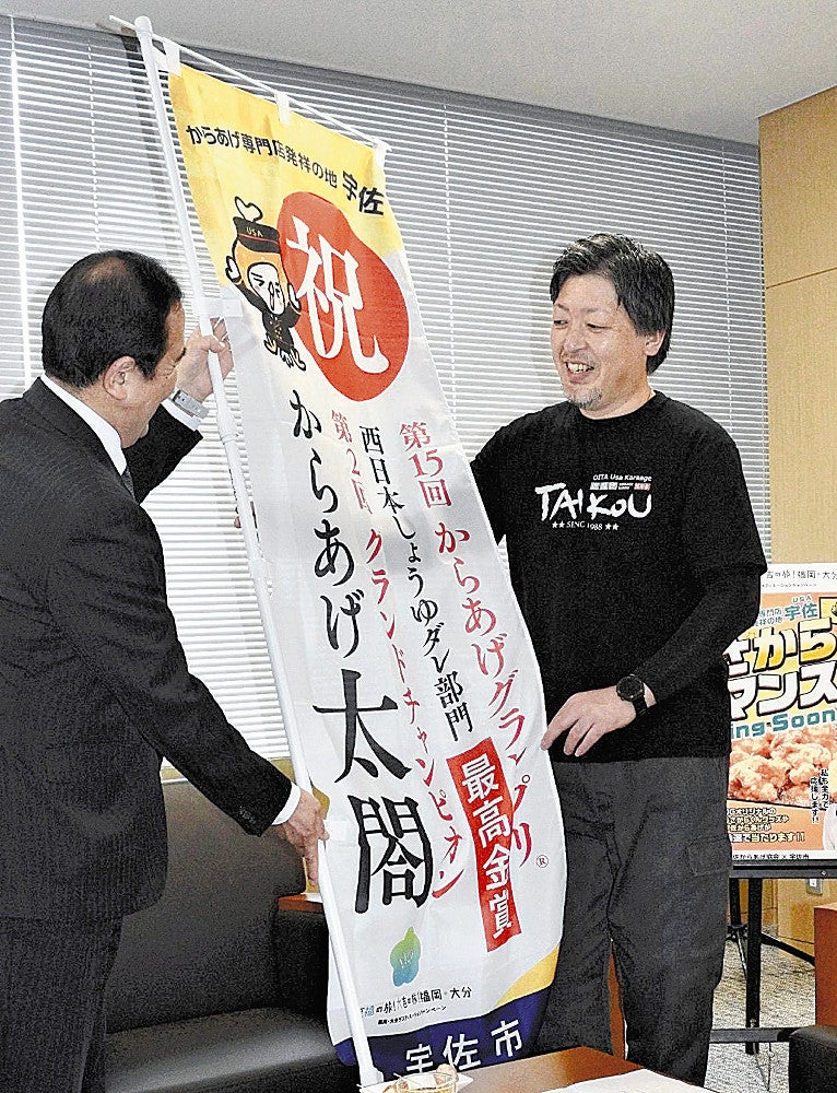 是永市長（左）から記念の旗を受け取る吉田さん