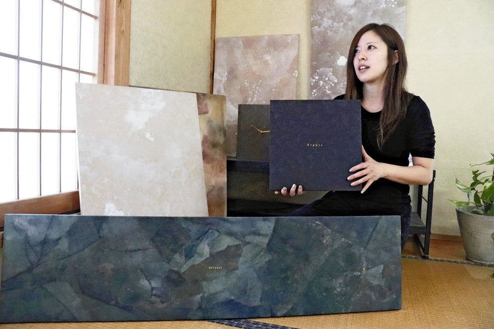 和紙製のボードを紹介する井上さん。手前の作品は、家族の絆が強固になるよう岩のイメージを重ねて制作した