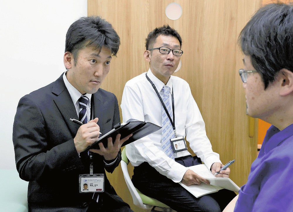 診療所を訪問し、医師に患者紹介を依頼する大阪市立十三市民病院の堀島さん（左）ら（２２日、大阪市淀川区で）＝前田尚紀撮影