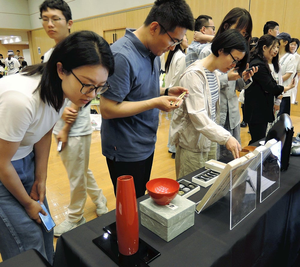 会場に展示された輪島塗に関心を示す中国人参加者ら（１日、北京の日本大使館で）＝川瀬大介撮影